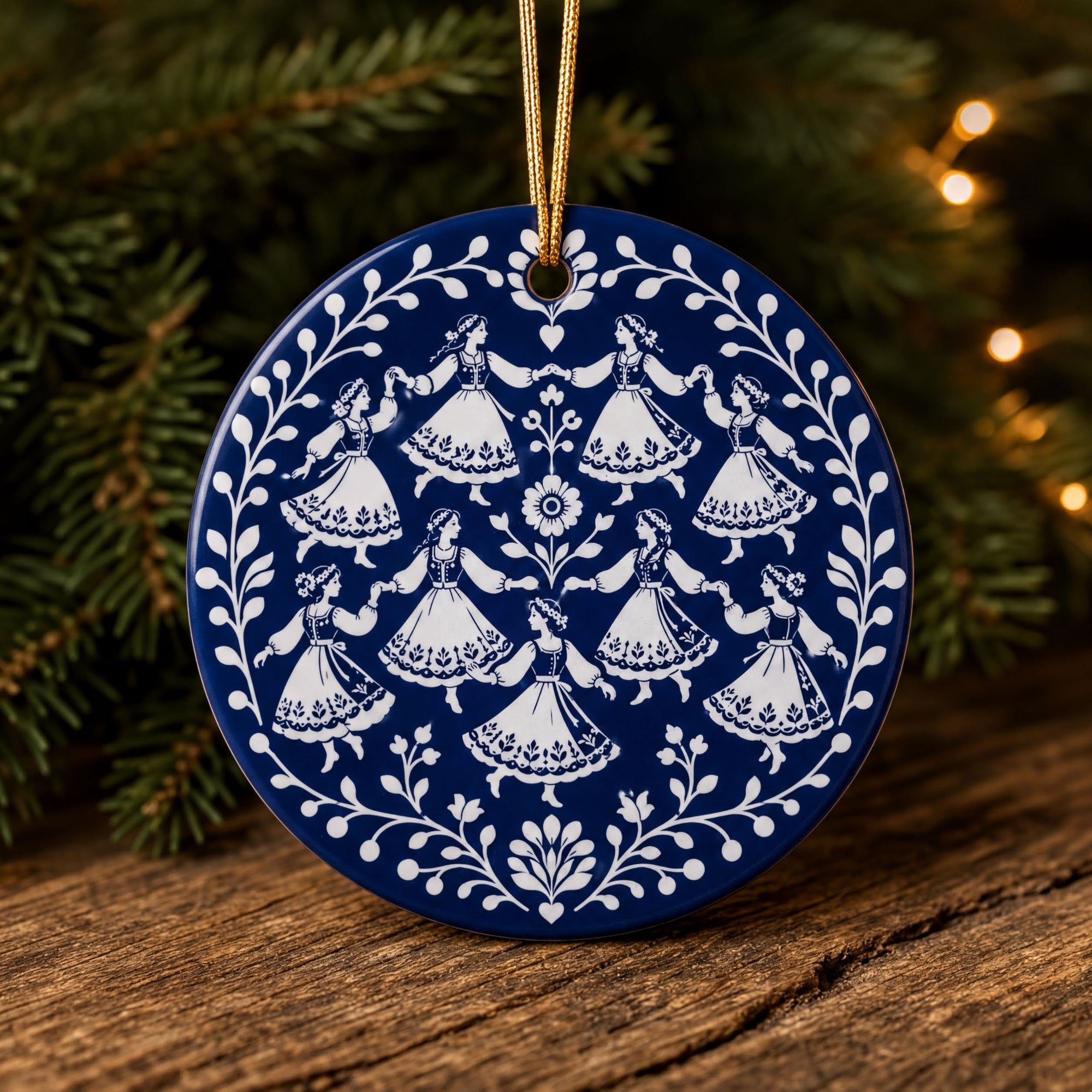 A blue and white ornament featuring a floral design with white figures holding flowers, hanging on a string.